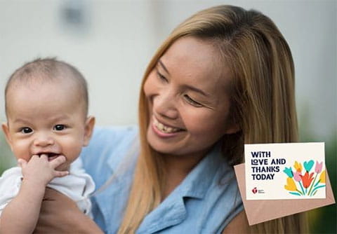 Mother holding baby. Both are smiling.