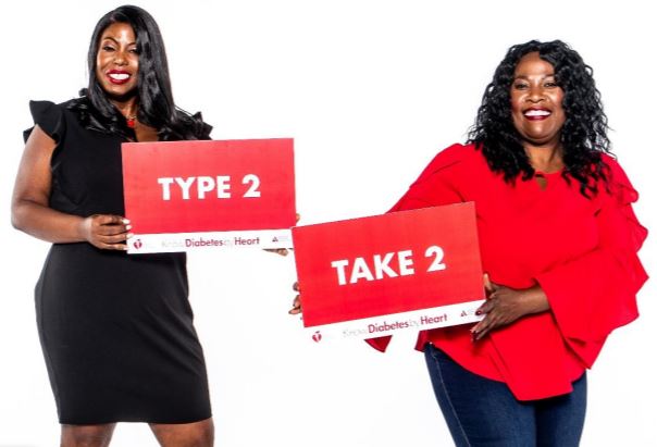 A Black woman on the left is hold a sign that reads, "Type 2," and a Black woman on the right is holding a sign that reads, "Take 2."