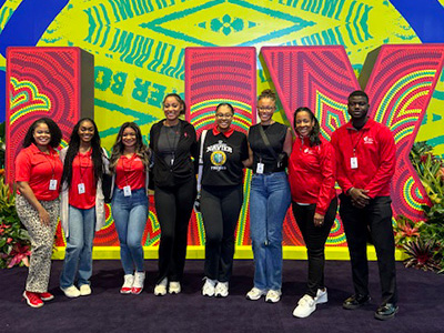 A group of AHA Scholars standing in front of a Super Bowl LIX sign