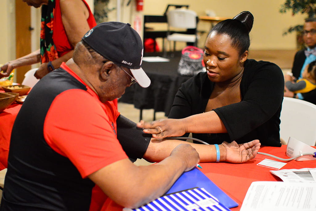 Nurse checking a man's blood pressure at a parish center 