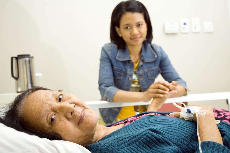 mother in hospital bed holding daughter's hand