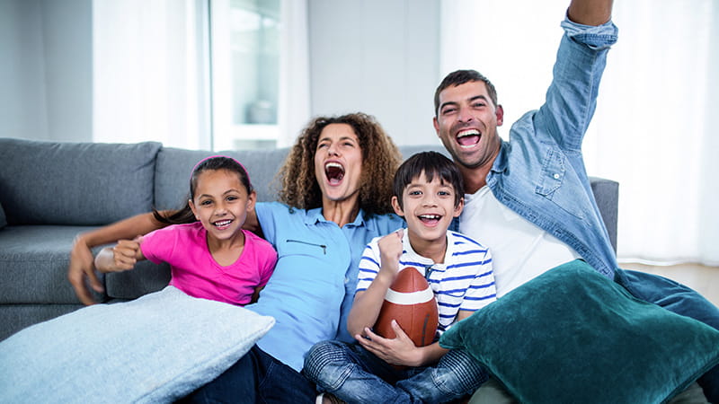 Family watching american football match on television at home