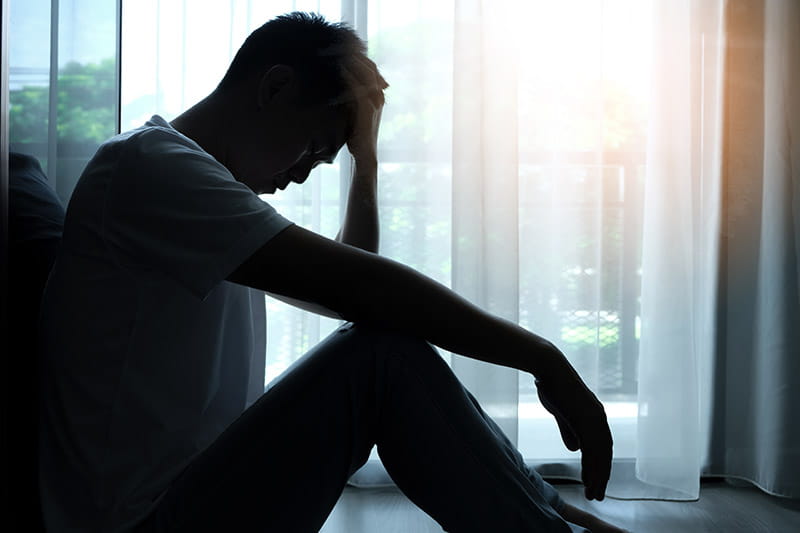 The man sitting in the corner of the room has emotional and mental problems.