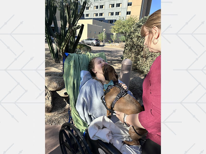 Alyssa Reader visiting with her dog Winston, with some help from Natalie Reader, during a hospital visit