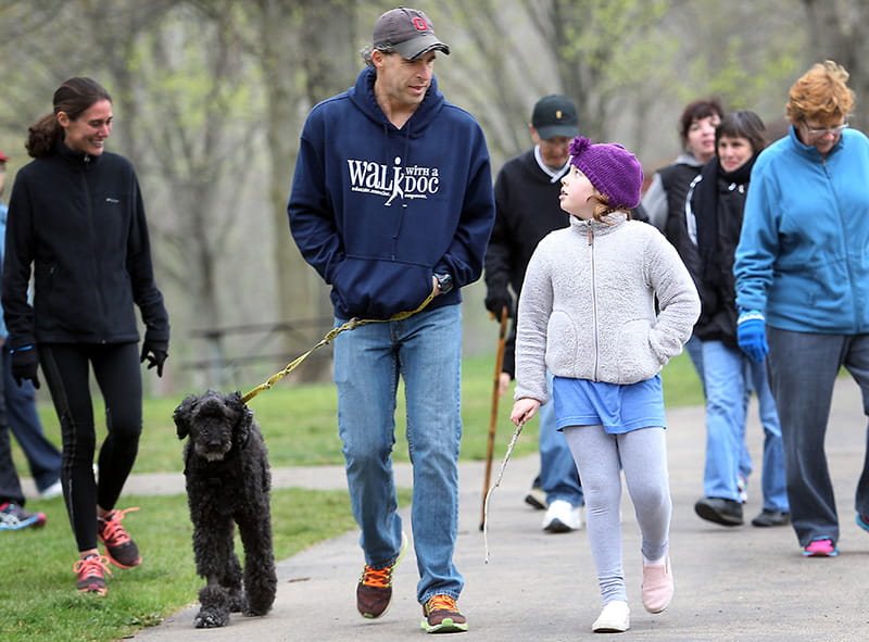 Dr. David Sabgir, founder of Walk With a Doc, on a walk with his dog, Mudge, his wife, Kristin (far left) and others in 2016
