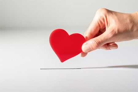 A hand holding a small paper heart