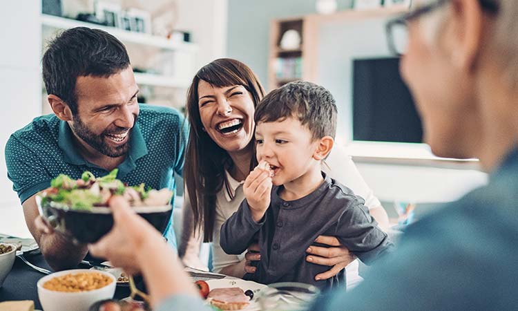 Family laughing and eating dinner together.