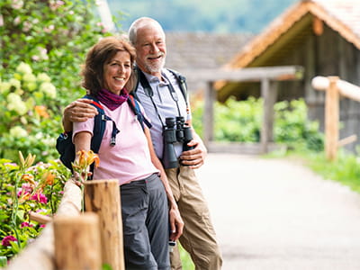 Older couple wearing binoculars and backpacks on an adventure