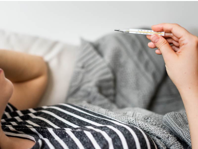 Woman in bed with thermometer.